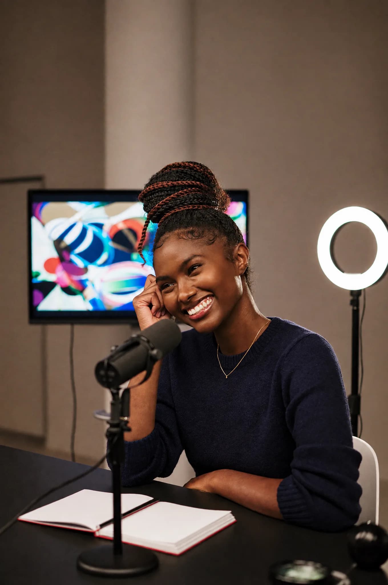 An online course creator smiling as she records a lesson at her microphone